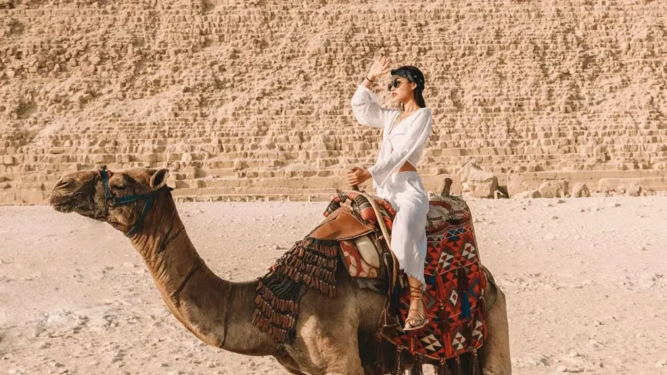 Tourists riding camels with the Great Pyramid of Giza in the background