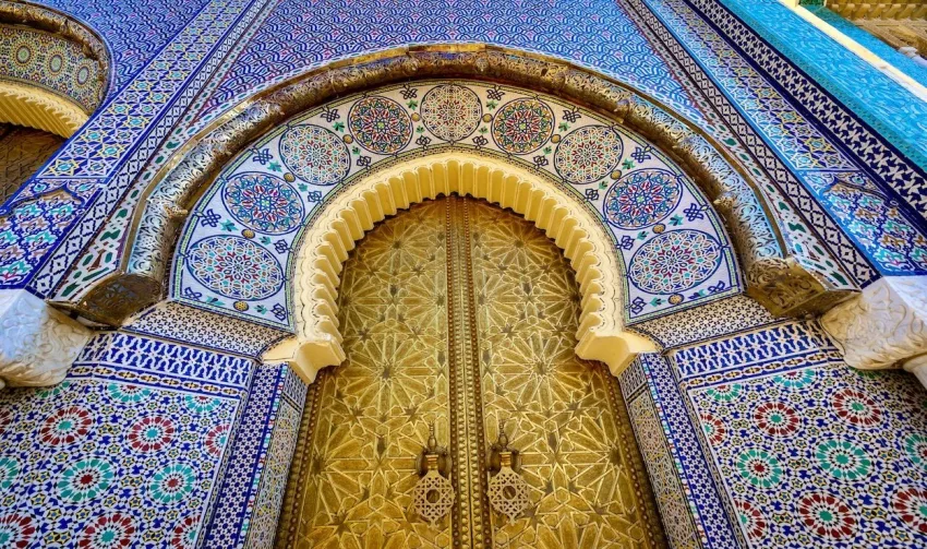 Interior of a Fes riad featuring intricate mosaic walls, and traditional Moroccan decor.